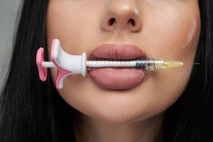 woman holding syringe with lip filler